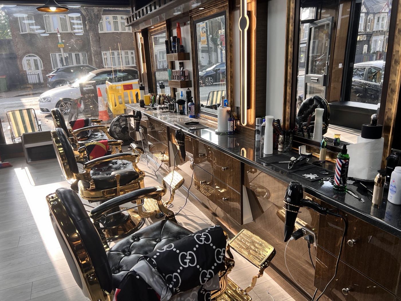 Inside Bstar Barber — gold and black barber chairs and styling stations, with Prince Regent Lane through the window